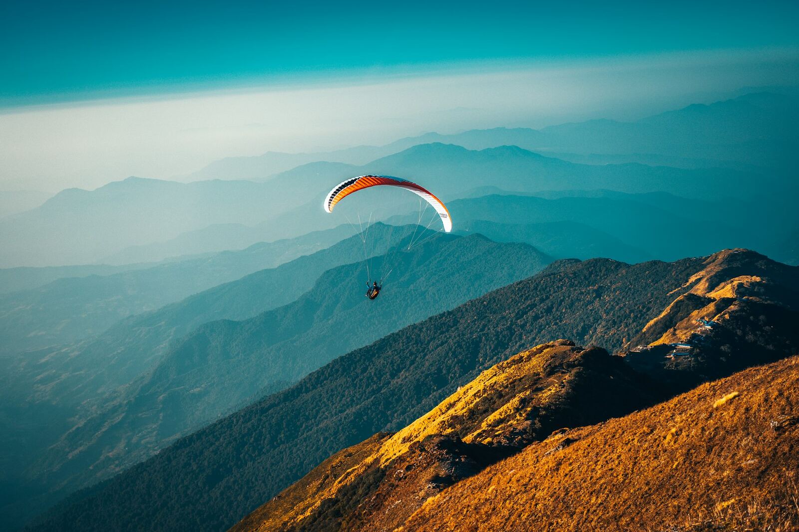 Paraglider flying over mountain ridges